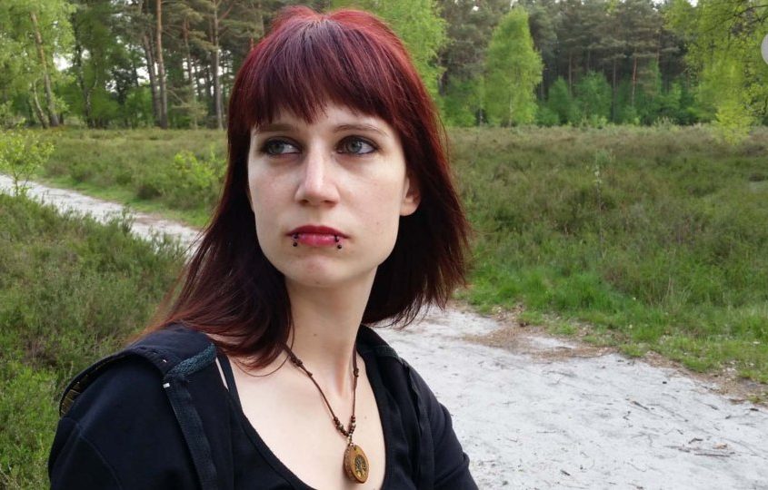 Julia vor ländlicher Umgebung. Sie steht auf einer Straße.